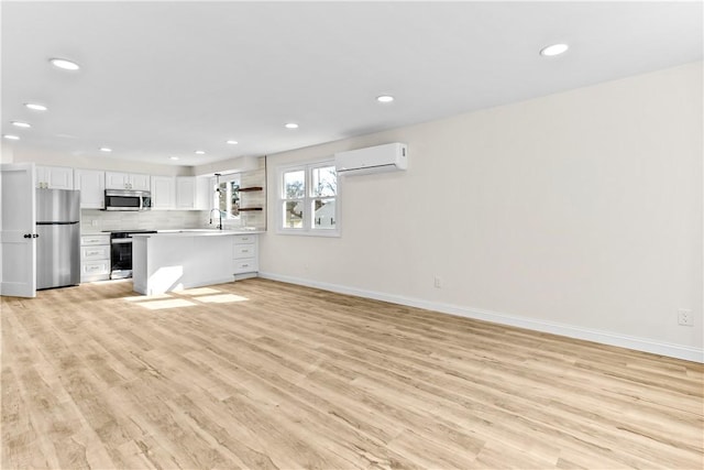 unfurnished living room featuring a wall mounted AC, light wood finished floors, baseboards, recessed lighting, and a sink