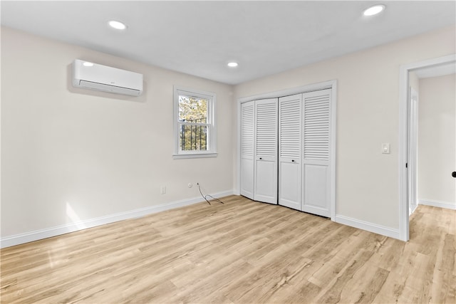 unfurnished bedroom with baseboards, a wall unit AC, light wood-style flooring, and recessed lighting