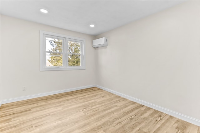 unfurnished room with light wood finished floors, baseboards, a wall mounted AC, and recessed lighting