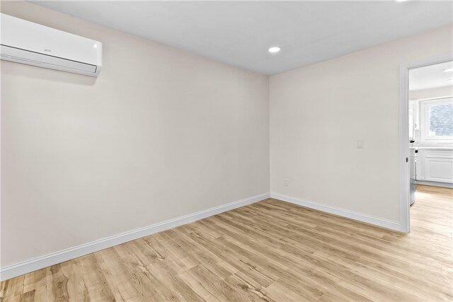 empty room with recessed lighting, an AC wall unit, baseboards, and light wood-type flooring