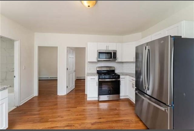 57 School St, East Providence, RI 02914 - kitchen with white cabinets, light wood finished floors, tasteful backsplash, appliances with stainless steel finishes, and a baseboard heating unit