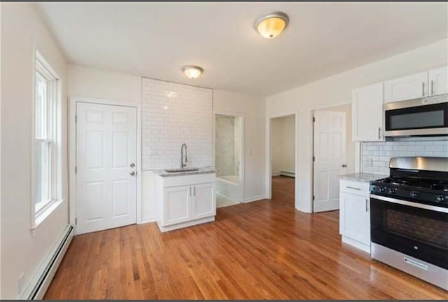 57 School St, East Providence, RI 02914 - kitchen with a baseboard radiator, light wood-style flooring, a sink, and stainless steel appliances