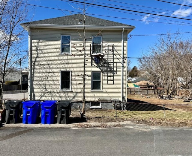 view of side of property featuring a shingled roof and fence private yard