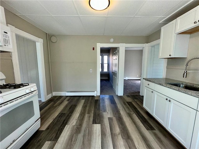 kitchen featuring a baseboard heating unit, white appliances, dark stone counters, a sink, and baseboard heating