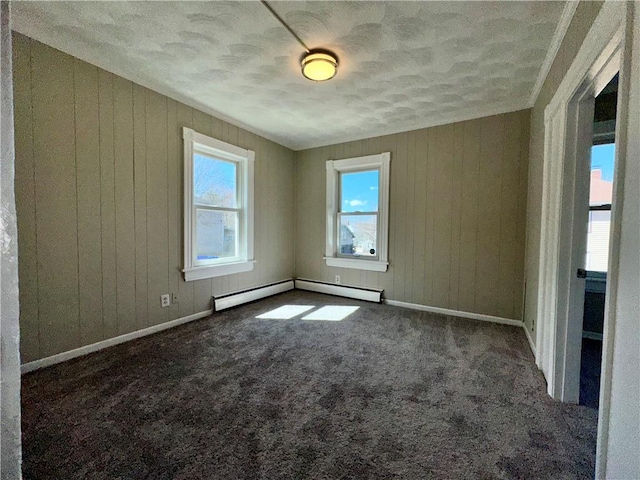 unfurnished room with baseboards, wooden walls, a baseboard radiator, and dark colored carpet