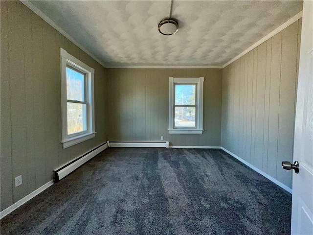 empty room featuring baseboards, baseboard heating, crown molding, and dark carpet