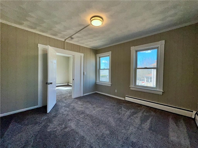 unfurnished room with ornamental molding, dark carpet, and a baseboard heating unit
