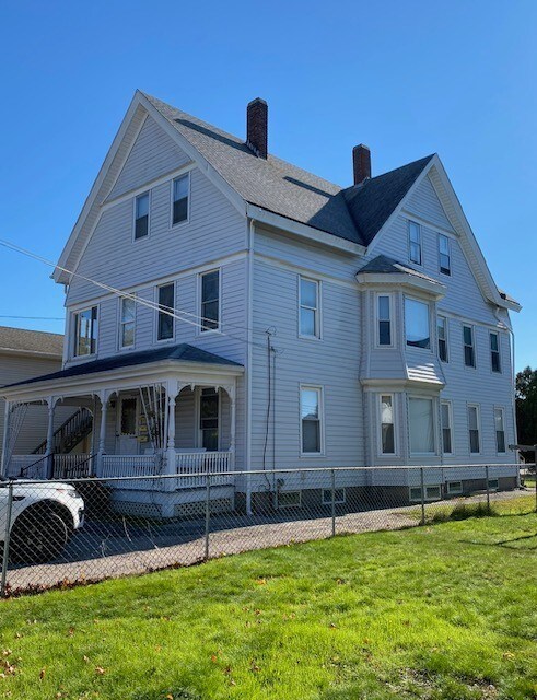 exterior space with covered porch, a fenced front yard, a yard, and a chimney