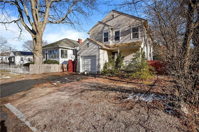 traditional-style house with fence, a garage, and aphalt driveway