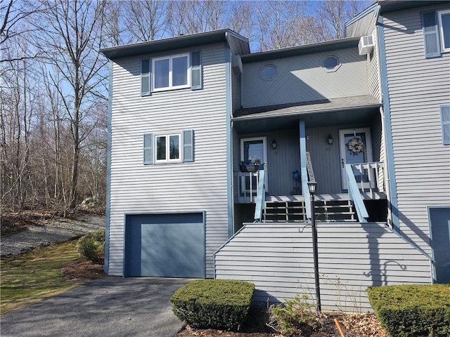 view of front facade with stairs, covered porch, a garage, and aphalt driveway