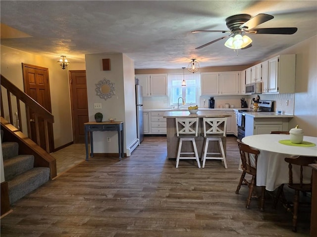 kitchen featuring light countertops, a kitchen island, appliances with stainless steel finishes, white cabinetry, and a sink
