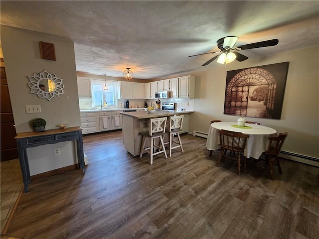 kitchen featuring dark wood-style flooring, white cabinets, a sink, a kitchen breakfast bar, and stainless steel electric stove
