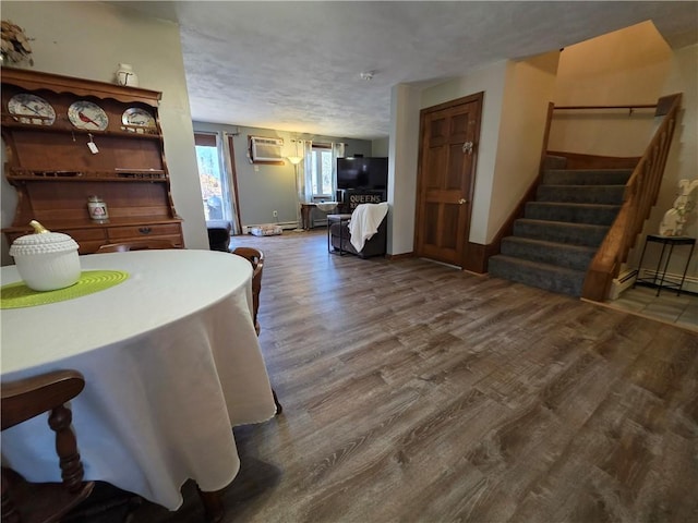 dining area featuring stairs, a textured ceiling, wood finished floors, and an AC wall unit