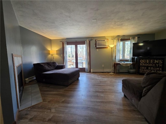 living room featuring a wall mounted air conditioner, a textured ceiling, wood finished floors, and a baseboard radiator