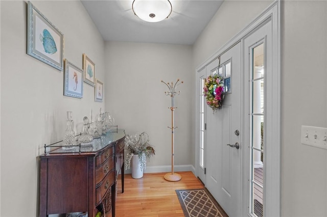 foyer entrance with baseboards and light wood-style flooring