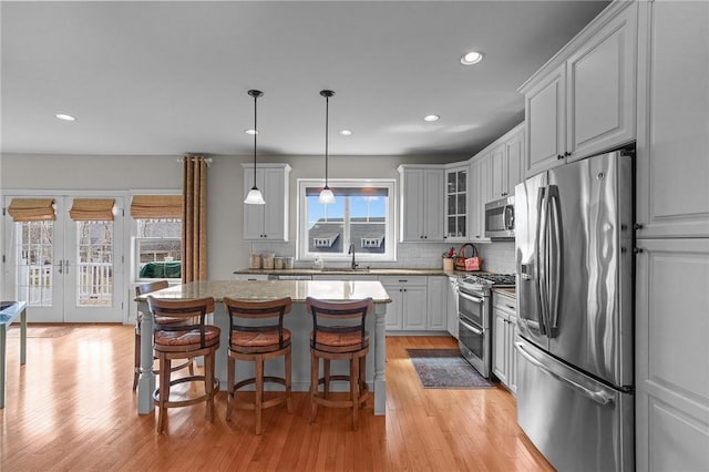 kitchen with stainless steel appliances, tasteful backsplash, glass insert cabinets, a sink, and french doors