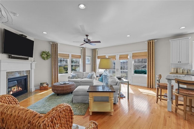 living area featuring baseboards, ceiling fan, recessed lighting, light wood-style floors, and a glass covered fireplace