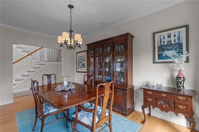 dining room with stairs, crown molding, wood finished floors, baseboards, and an inviting chandelier