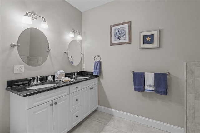 full bath with baseboards, double vanity, a sink, and tile patterned flooring