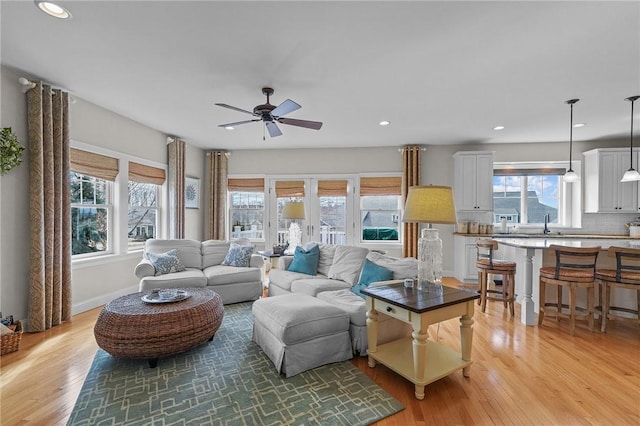 living room featuring baseboards, light wood-type flooring, ceiling fan, and recessed lighting