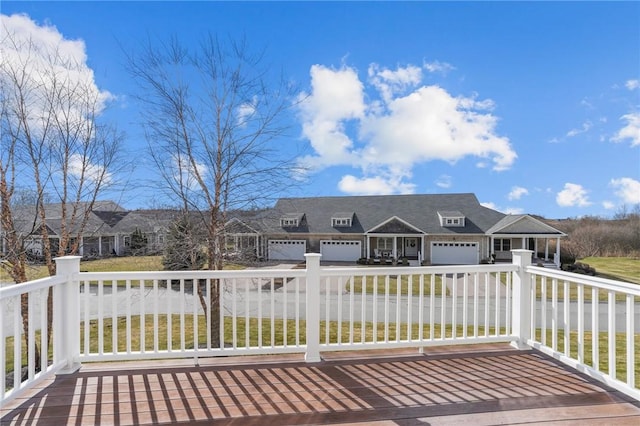 wooden terrace with a fenced front yard, a garage, and concrete driveway