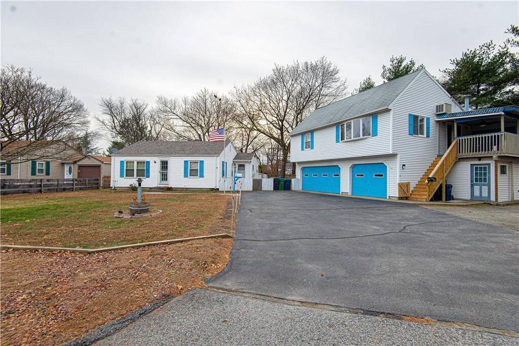 view of front of property featuring aphalt driveway, fence, an attached garage, stairway, and a front yard