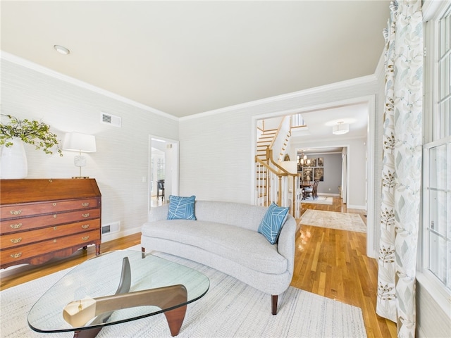 living area with wood finished floors, visible vents, ornamental molding, and baseboards