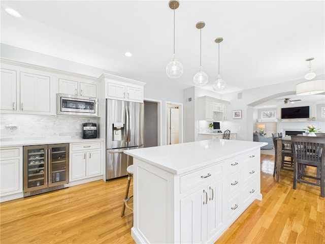 kitchen with light countertops, appliances with stainless steel finishes, light wood-style flooring, and wine cooler