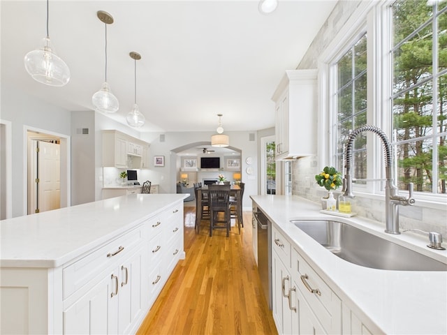 kitchen with light countertops, plenty of natural light, stainless steel dishwasher, and a sink