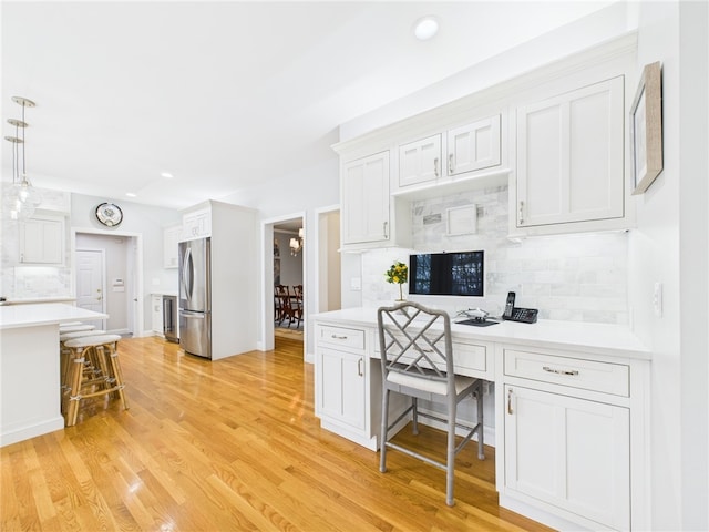 kitchen with built in study area, freestanding refrigerator, decorative backsplash, and light countertops