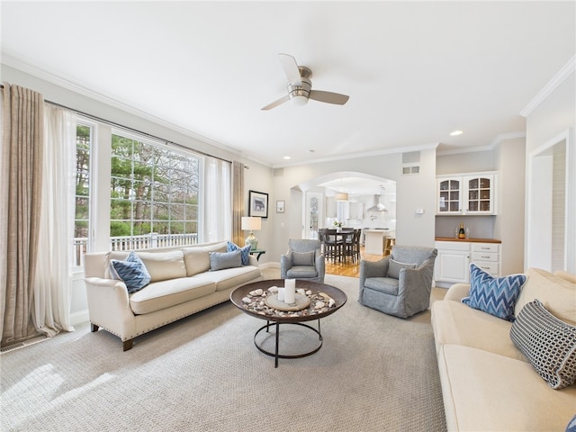 living room with visible vents, arched walkways, a ceiling fan, and crown molding