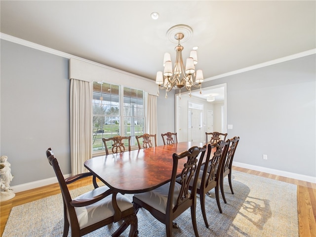 dining area with ornamental molding, light wood-type flooring, a notable chandelier, and baseboards
