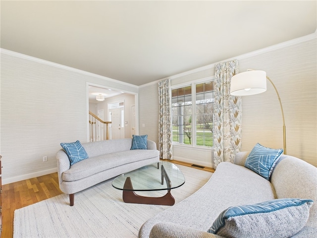 living area with wood finished floors, stairway, ornamental molding, baseboards, and visible vents