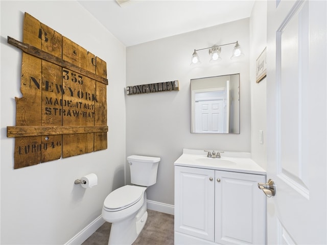 half bath with baseboards, toilet, and vanity