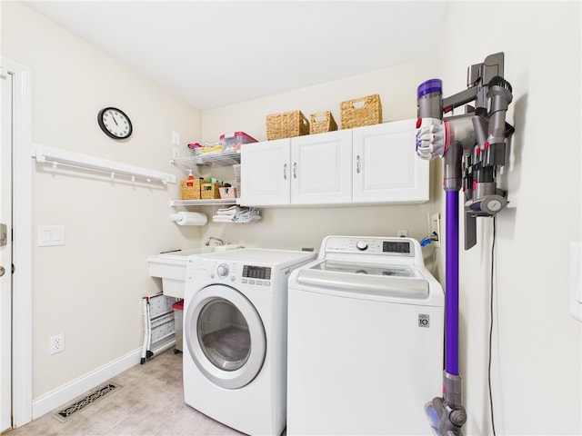 laundry area featuring baseboards, visible vents, cabinet space, and washer and clothes dryer