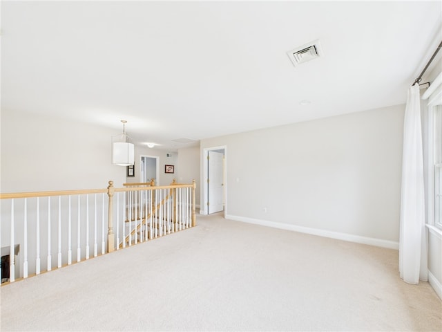 empty room featuring visible vents, light carpet, and baseboards