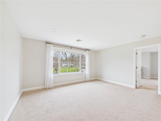 spare room with baseboards, visible vents, and light colored carpet