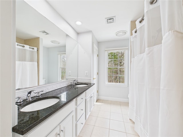 bathroom featuring tile patterned floors, visible vents, double vanity, and a sink