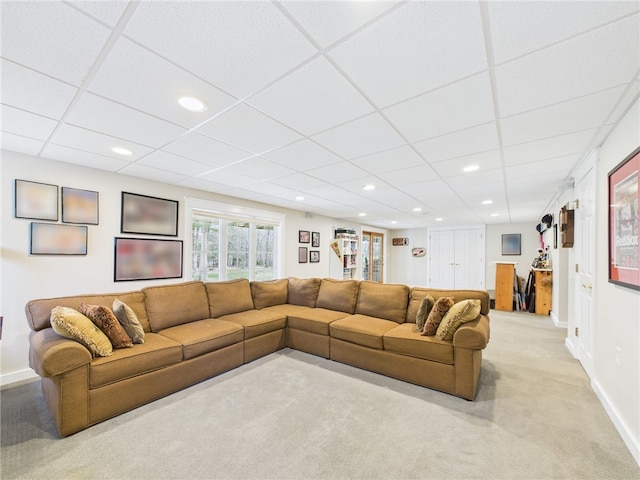 living room with a drop ceiling, baseboards, recessed lighting, and light carpet
