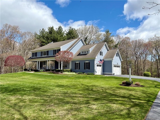 traditional-style house with a front yard, driveway, an attached garage, and covered porch
