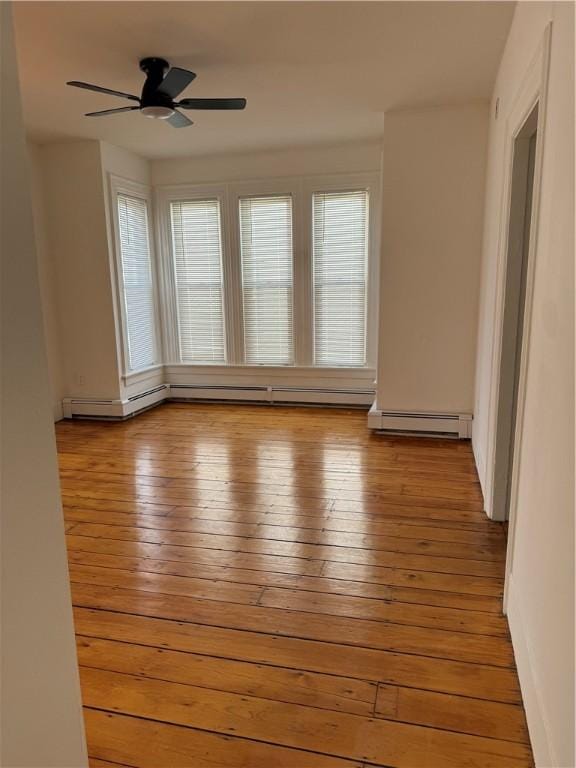 unfurnished room with light wood-style floors, a ceiling fan, and baseboard heating