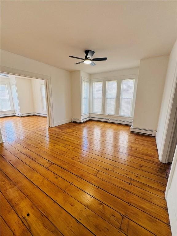 empty room with wood-type flooring, a ceiling fan, baseboards, and a baseboard heating unit