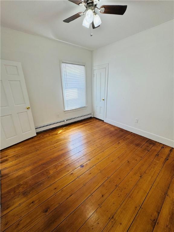 unfurnished room with wood-type flooring, a ceiling fan, baseboards, and baseboard heating
