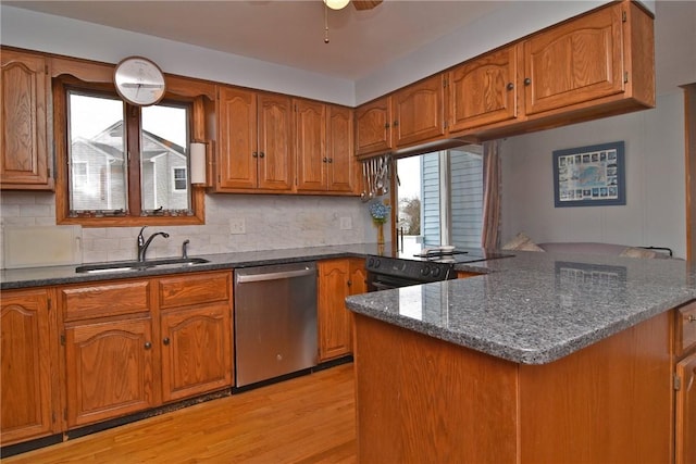 kitchen with light wood-style floors, a sink, stainless steel dishwasher, and brown cabinets