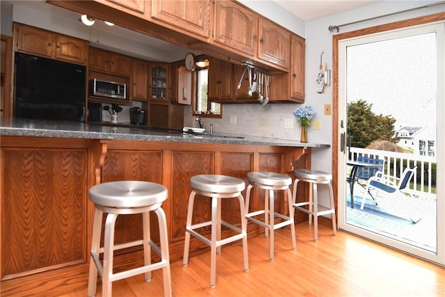 kitchen with fridge, brown cabinetry, and stainless steel microwave