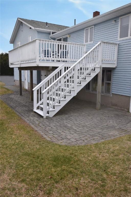 rear view of house with stairs, a patio, a wooden deck, a yard, and a chimney