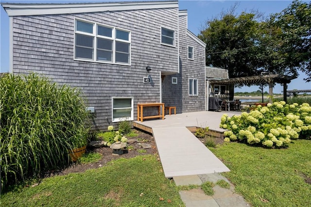 back of property featuring a lawn, a pergola, and a patio area