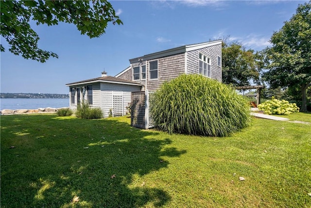 view of home's exterior with a pergola, a water view, and a lawn