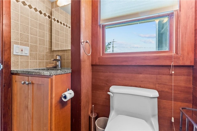 half bath with backsplash, toilet, and vanity