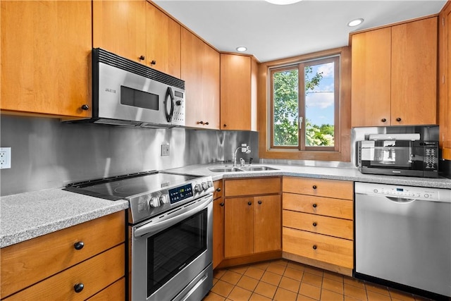 kitchen with light tile patterned floors, a sink, stainless steel appliances, and light countertops